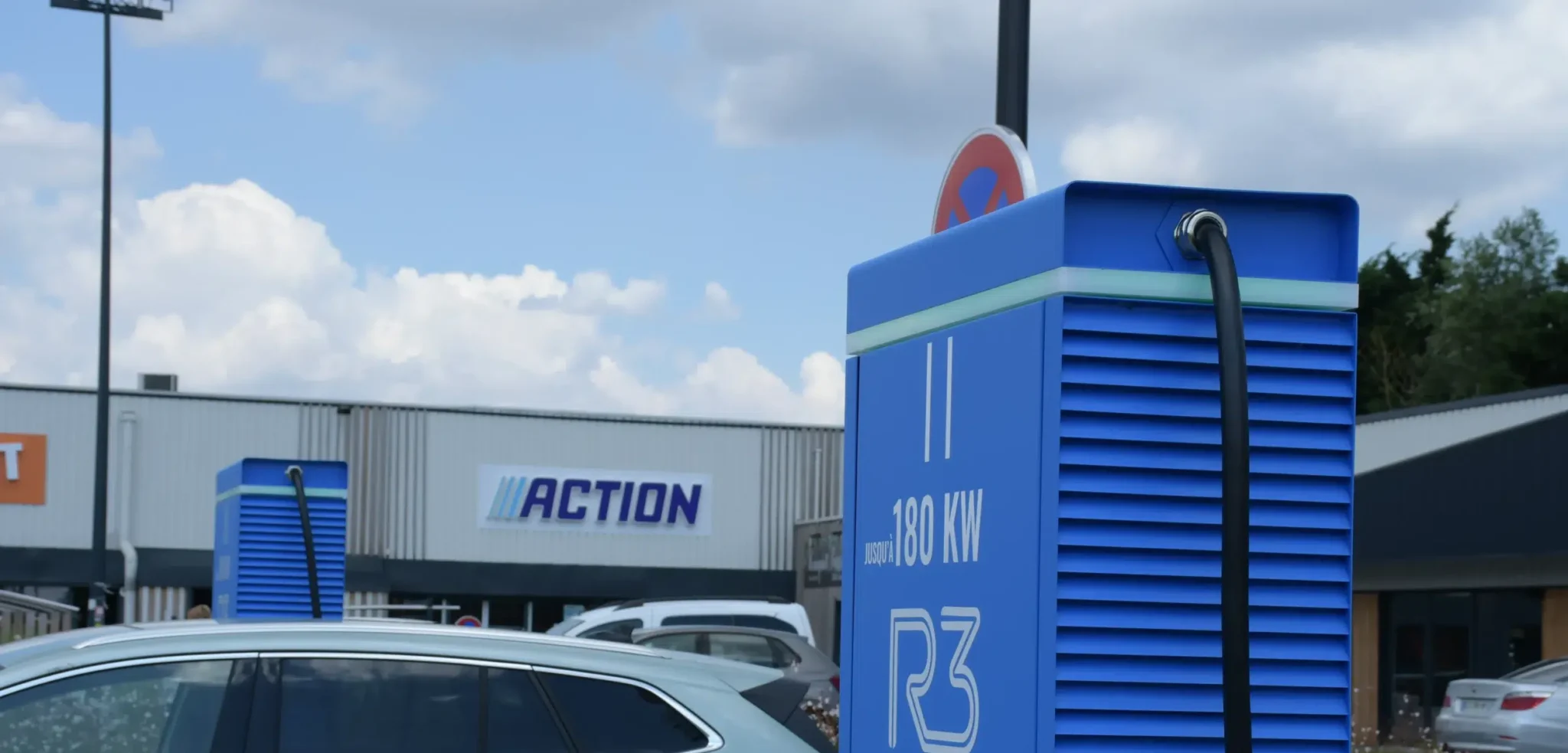 Borne de recharge rapide 180 kw pour voiture électrique installée sur un parking de centre commercial, véhicule électrique stationné en charge, infrastructure de mobilité durable facilitant la recharge lors des déplacements quotidiens.