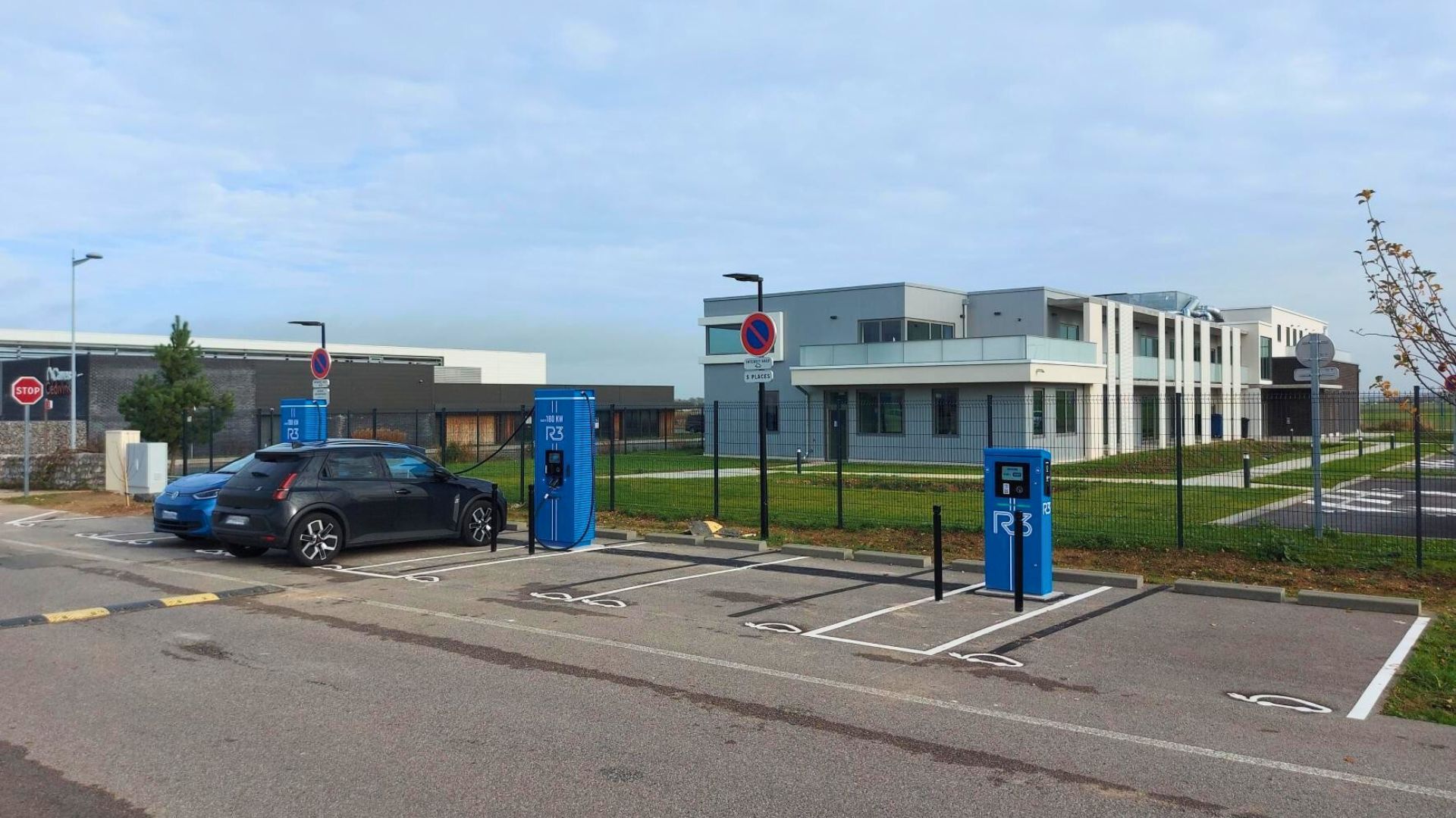 Bornes de recharge électrique sur parking moderne devant un bâtiment tertiaire, mobilité durable et infrastructure urbaine