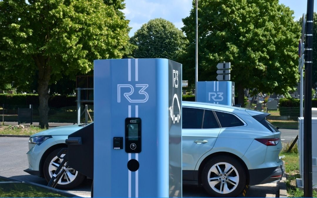 Borne de recharge électrique R3 installée en extérieur avec voiture branchée, solution de mobilité durable en station moderne