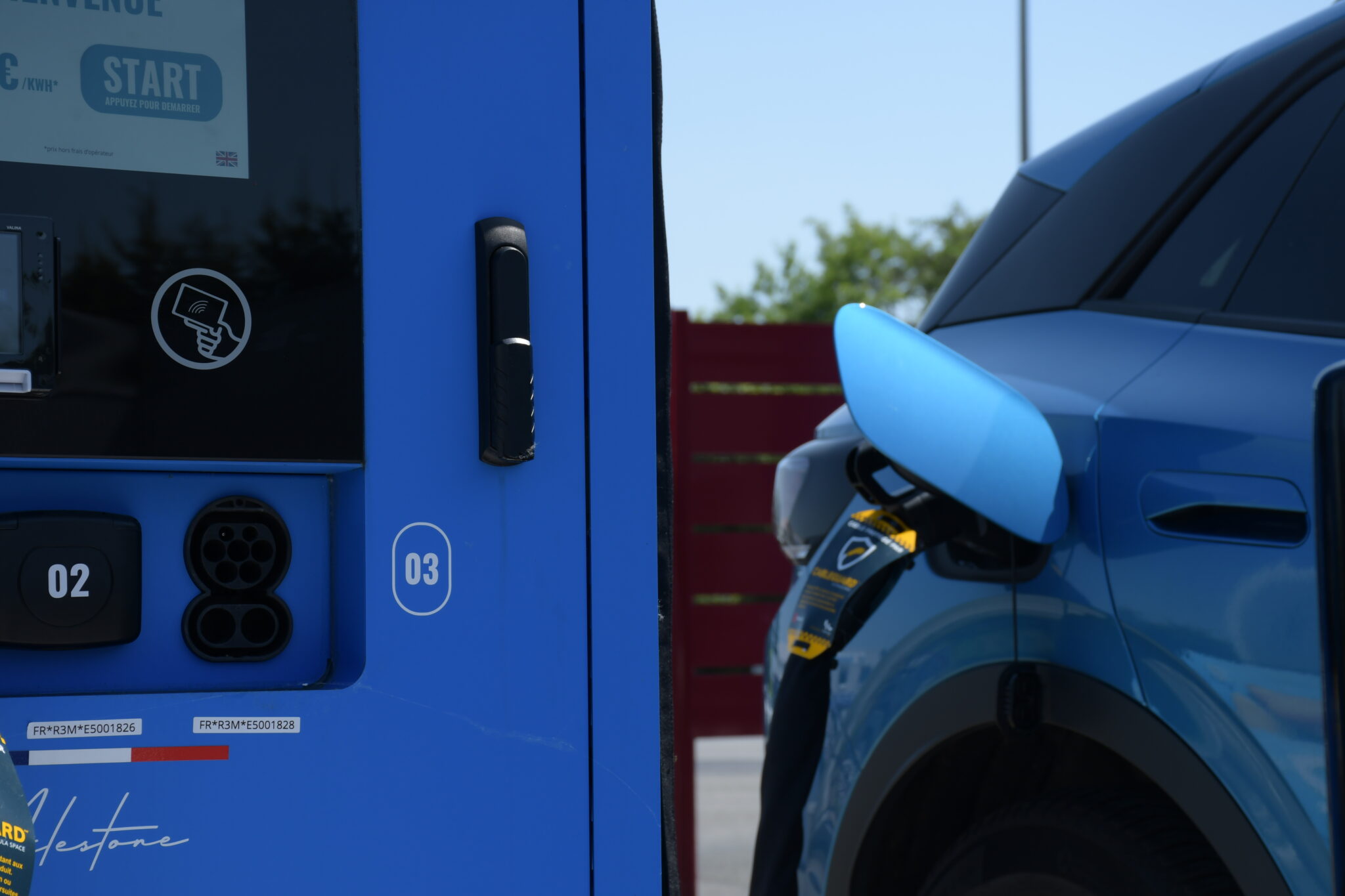 Photo qui montre une voiture électrique avec une borne de recharge de voiture électrique
